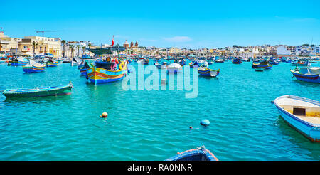 Panorama du port de Marsaxlokk avec de nombreux bateaux en bois et dériveurs, posés sur les vagues, de Malte. Banque D'Images