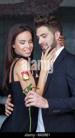 Jeune homme élégant rose rouge donner pour femme à l'intérieur de Jour de Valentines Banque D'Images