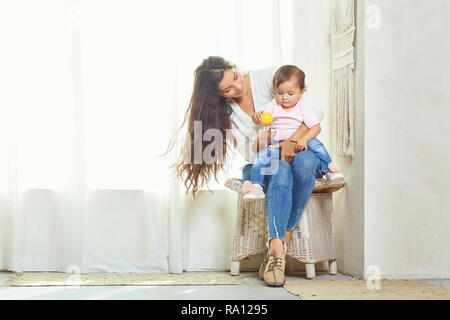 Mère brunette joue avec l'enfant à la maison. Banque D'Images