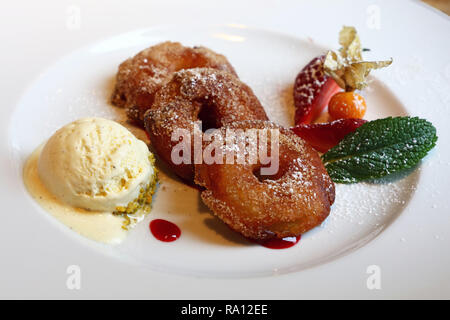 Close up partie de deep fried sweet apple rings battues avec de la crème glacée et de baies sur plaque blanche, dessert traditionnel de l'allemand de Bavière cuis Banque D'Images