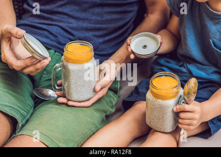 Père et fils manger le dessert avec chia seeds et de mangues à la piscine le matin. la saine alimentation, l'alimentation, les régimes végétariens et personnes concept Banque D'Images