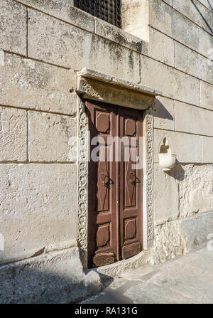 Une porte en bois avec croix en pierre entourent et rayé dans le travail de la pierre Banque D'Images
