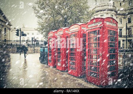 Scène de rue à Londres l'hiver avec les cabines téléphoniques rouges emblématique avec la neige qui tombe Banque D'Images