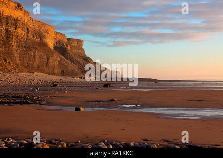 À la recherche vers le sud en direction de Nash Point le long de la plage jonchée de rock point Nash avec en arrière-plan et de deux personnes, l'un se tenait en haut des rochers. Banque D'Images