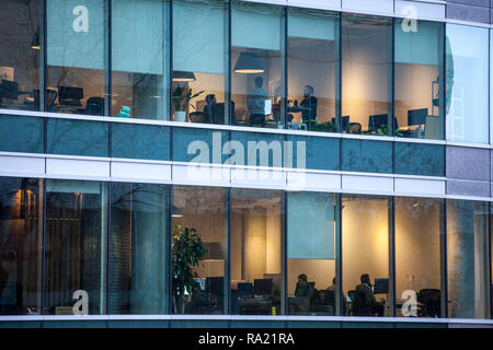 Montréal, Canada - le 6 novembre 2018 : Les personnes qui travaillent dans les espaces ouverts des bureaux dans un gratte-ciel, vu de l'extérieur, le soir, à Montréal, Québec Banque D'Images