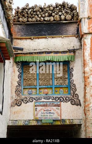 Fenêtre ornée sur le mur d'une maison tibétaine à Lo Manthang, Upper Mustang région, le Népal. Inscrivez-vous pour un magasin de souvenirs sur la partie inférieure de l'image. Banque D'Images