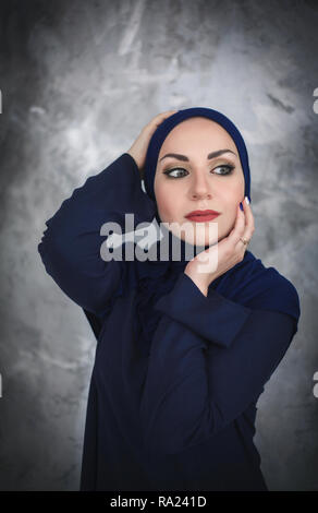 Belle jeune femme arabe en vêtements traditionnels en studio sur fond gris. Banque D'Images