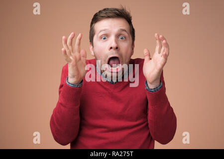 Homme d'être choqué à la caméra à large avec bouche ouverte et yeux criant avec horreur d'écoute. Banque D'Images