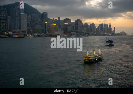 Le Star Ferry de croisière sur le port et de l'Aqua Luna'junk font leur commerce de nuit contre la toile de fond spectaculaire de l'île de Hong Kong Banque D'Images