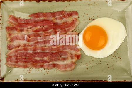 Close up petit-déjeuner anglais, côté ensoleillé et d'œufs les tranches de bacon grillé sur plaque bleue, augmentation de la vue supérieure, juste au-dessus Banque D'Images