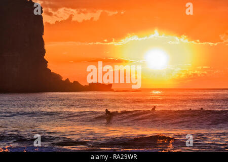 Bloody soleil orange sur horizon de mer vagues inondations avec des planches au large de la plage d'Avalon en Australie Sydney plages du nord sur la côte Pacifique. Banque D'Images