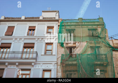 Un vieux bâtiment abandonné couvert de filet vert à côté d'un bâtiment restauré et rénové dans la vieille ville de Valence, en Espagne. Banque D'Images