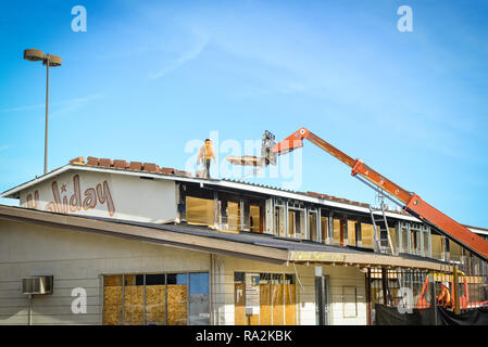 Un travailleur de la construction portent un casque marche sur le long deliverying avec toit grue palette de tuiles d'argile pour remodeler de toit sur un vieux motel à Las Vegas Banque D'Images