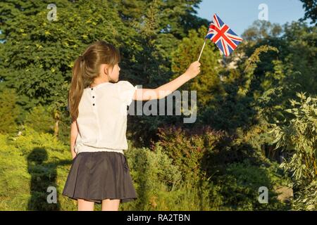 Petite fille avec le drapeau de Grande-bretagne dans sa main, sous le soleil de l'été parc. Banque D'Images