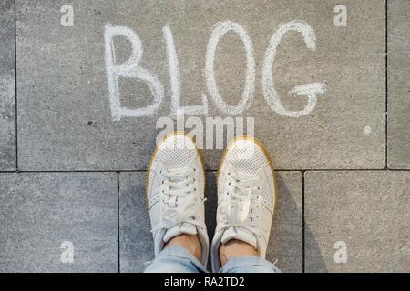 Vue de dessus, les pieds avec texte blog écrit sur le trottoir gris. Banque D'Images