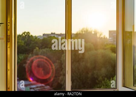 Ouvrez les fenêtres dans l'appartement. Coucher de soleil en arrière-plan, la silhouette de la ville. Banque D'Images