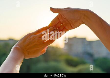 Mains montrant geste des doigts, symbole de l'amitié et relation. Coucher de soleil en arrière-plan, la silhouette de la ville. Banque D'Images