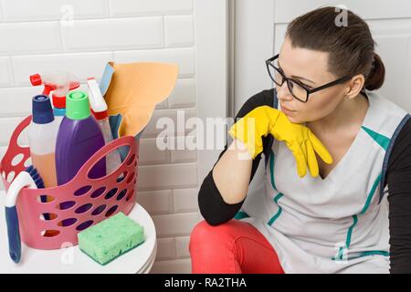 Tired woman sitting on salle de bains marbre avec des produits de nettoyage et d'équipement. Banque D'Images