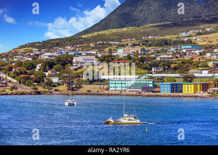 Voiliers amarrés au large de St Kitts près de Green Hills et maisons colorées Banque D'Images