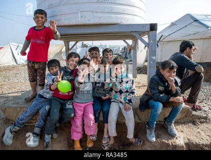 19 décembre 2018, l'Iraq, Hasan Sham : Les enfants observent la visite du Ministre des affaires étrangères de la Maas Hasan Sham camp de réfugiés et montrer la victoire. Le campement près de l'ancienne place forte est en grande partie détruite de Mossul peut accueillir 3 300 des 1,8 millions de personnes déplacées en Iraq. Photo : Jens Büttner/dpa-Zentralbild/ZB Banque D'Images