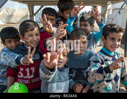 19 décembre 2018, l'Iraq, Hasan Sham : Les enfants observent la visite du Ministre des affaires étrangères de la Maas Hasan Sham camp de réfugiés et montrer la victoire. Le campement près de l'ancienne place forte est en grande partie détruite de Mossul peut accueillir 3 300 des 1,8 millions de personnes déplacées en Iraq. Photo : Jens Büttner/dpa-Zentralbild/ZB Banque D'Images