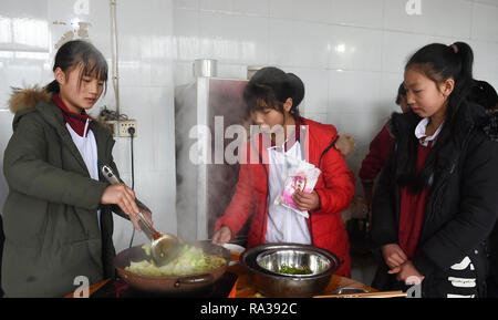 (190101) -- JULIAN, JAN. 1, 2019 (Xinhua) -- Jiang Qiao, Luo Shaoli et Liu Exécuter (G à D) de l'équipe de basket-ball cuisiner pour leurs coéquipiers à l'heure du déjeuner à Haoba central school dans le comté de Junlian de Yibin City dans le sud-ouest de la province chinoise du Sichuan, le 8 décembre 2018. L'hébergement des étudiants, les filles ont à cuisiner pour eux-mêmes pendant les week-ends. Situé dans le sud-ouest des montagnes de Wumeng vaste la province chinoise du Sichuan, Haoba central school est une école de neuf ans fournissant l'enseignement primaire et secondaire l'éducation, tout comme les autres écoles dans cette zone montagneuse. Cependant, une équipe de basket-ball créée par Banque D'Images