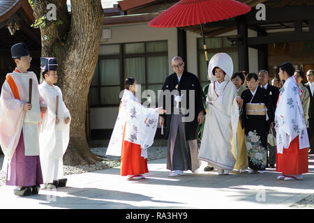 Mariage Shinto procession avec mariée de porter le watabōshi capot blanc traditionnel à marcher avec le marié dans le Sanctuaire Shinto de Meiji Jingu Banque D'Images