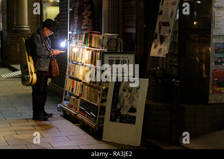 La lecture de livres à la clientèle sur la rue en face d'une librairie, Jimbocho, Kanda, Chiyoda, Tokyo Banque D'Images