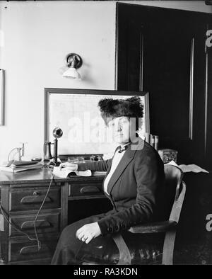 Woman sitting at desk with old telephone ca. 1910-1920