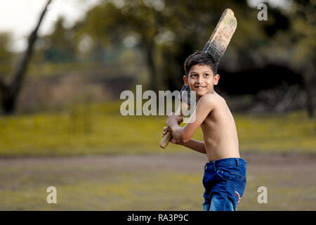 Enfant de l'Inde rurale à jouer au cricket Banque D'Images