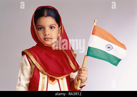 PORTRAIT D'UNE JEUNE FILLE DU PENDJAB DANS UN COSTUME TRADITIONNEL, tenant le drapeau national indien Banque D'Images