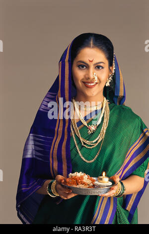 Le portrait d'une jeune mariée MAHARASHTRIAN MARATHI/habillé en SAREE traditionnel, tenant une cérémonie PUJA THALI/ navire doté d'une lampe allumée. Banque D'Images