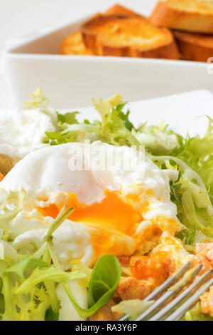 Salade française classique, grande salade lyonnaise. Vert plat à feuilles de laitue, sauce moutarde de Dijon avec des morceaux de bacon frit, grillé, pain français Banque D'Images