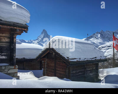 Cottages avec beaucoup de neige sur le toit et drapeau suisse en face de Matterhorn, Zermatt, Suisse Banque D'Images