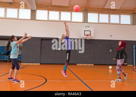 Les élèves à jouer au ballon dans la salle de sport, l'éducation physique, l'école primaire, Basse-Saxe, Allemagne Banque D'Images