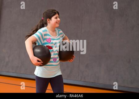 Lycéenne jouer au ballon dans la salle de sport, l'éducation physique, l'école primaire, Basse-Saxe, Allemagne Banque D'Images