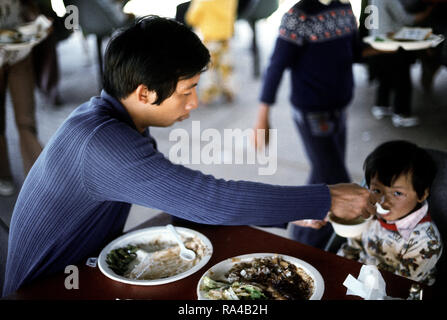 1975 - Un père nourrit ses enfants à un établissement de logements temporaires pour les réfugiés vietnamiens à Camp Pendleton, CA Banque D'Images