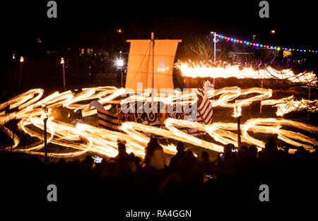 Une longue exposition photographie des boules de feu d'être balancé en rond autour d'un bateau viking au cours de la fête du Feu, Flamborough Viking un défilé à thème, le Nouvel An, à Flamborough près de Bridlington, Yorkshire, au profit d'organismes de bienfaisance et des groupes communautaires locaux. Banque D'Images