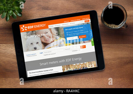 Le site internet de EDF Energy est vu sur une tablette iPad, sur une table en bois avec une machine à expresso et d'une plante (usage éditorial uniquement). Banque D'Images