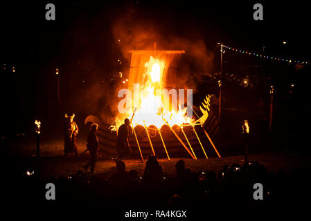 Les gens en costumes Viking en face d'un bateau viking brûlant pendant la fête du Feu, Flamborough Viking un défilé à thème, le Nouvel An, à Flamborough près de Bridlington, Yorkshire, au profit d'organismes de bienfaisance et des groupes communautaires locaux. Banque D'Images