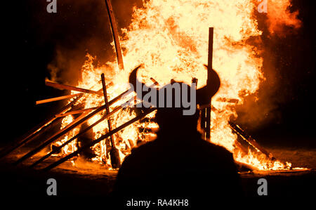 Une personne en costume Viking en face d'un bateau viking brûlant pendant la fête du Feu, Flamborough Viking un défilé à thème, le Nouvel An, à Flamborough près de Bridlington, Yorkshire, au profit d'organismes de bienfaisance et des groupes communautaires locaux. Banque D'Images