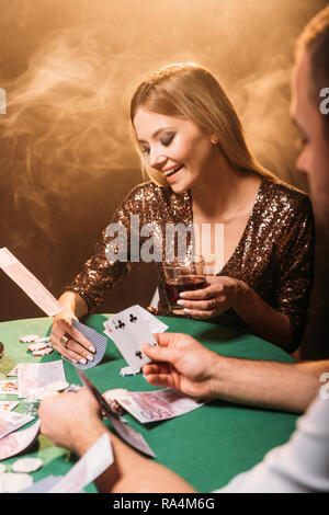 Smiling attractive girl jouant au poker avec croupier au Casino, les billets en euros qui tombent sur le tableau Banque D'Images