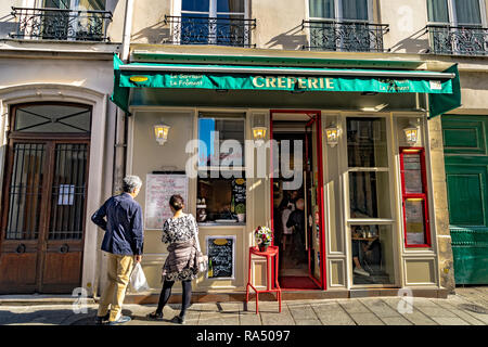 Un homme et une femme se tient en dehors de la lecture du menu déroulant au sarrasin et le froment Crêperie sur rue Saint-Louis en l'Île , Paris Banque D'Images