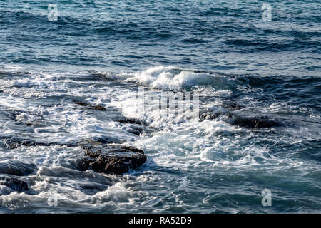 Pierres côtières en écumant des vagues de la mer bleue Banque D'Images