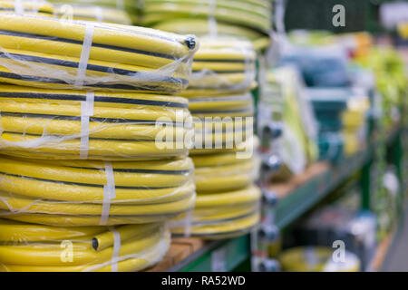 Des piles de rouleaux pvc jaune le tuyau en plastique sur le comptoir du magasin. Vente les flexibles dans le jardin de divers fabricants, sur les étagères de magasin. Pour flexible Banque D'Images