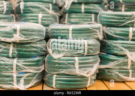 Des piles de rouleaux pvc jaune le tuyau en plastique sur le comptoir du magasin. Vente les flexibles dans le jardin de divers fabricants, sur les étagères de magasin. Pour flexible Banque D'Images