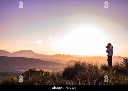 L'homme au sommet d'une montagne contre foggy landscape. Activités de plein air hivernales. Reflets de l'objectif. Banque D'Images