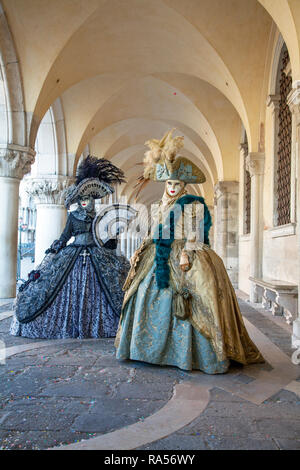 Déguisements et masques vénitiens en argent et or noir sous l'arcade du Palais des Doges pour le Carnaval de Venise, Venise Italie Banque D'Images