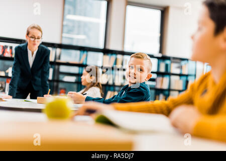 Enseignant à des élèves à l'étude à un bureau dans la bibliothèque Banque D'Images