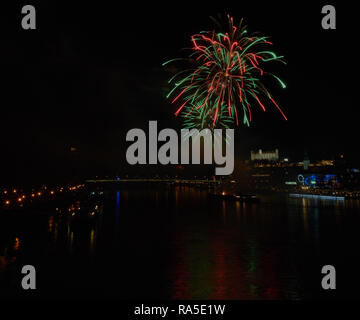 Feux d'artifice sur le Danube à Bratislava la nuit, avec le château de Bratislava qui brille sur l'horizon. Banque D'Images